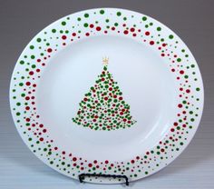 a white plate with a christmas tree painted on the front and green dots around it