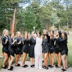 a group of women standing next to each other wearing black robes and holding champagne bottles