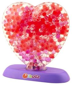 a heart shaped object with lots of red and pink beads on it's surface