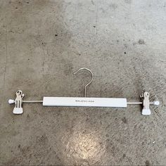 a white coat hanger on the ground with two hooks hanging from it's side