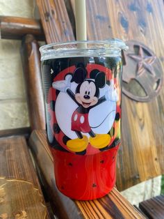 a mickey mouse cup sitting on top of a wooden bench