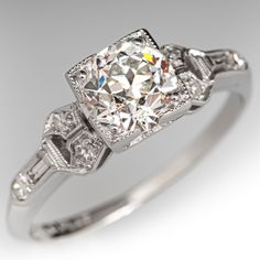 This lovely architectural circa 1920s Art Deco ring is centered with one (1) old European cut diamond, weighing 0.95 carats, that is prong set in a square frame with milgrain edging. Each shoulder is accented with three (3) bead set round single cut diamonds, and one (1) bezel set baguette cut diamond. The shoulders also have milgrain edges. The ring measures 6.2mm at the top, rises 6.1mm above the finger, tapering to 1.3mm wide and 1.0mm thick at the base of the shank.  The ring is crafted in platinum and is currently a size 5.  One of the baguette diamonds has a tiny corner chip that cannot be seen while worn. Luxury Single Diamond Art Deco Ring, Luxury Diamond White Sapphire Art Deco Ring, Luxury Art Deco Ring With Polished Finish, 3 Diamond Ring Settings Square, Luxury Art Deco White Sapphire Ring, Luxury Vintage Baguette Cut Diamond Ring, Luxury Art Deco Diamond Ring With Prong Setting, Luxury Art Deco Platinum Halo Ring, Luxury Princess Cut Art Deco Diamond Ring