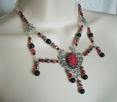 "This beautiful necklace has red glass beads, black pearl beads, seed beads, sterling silver plated filigree beads, pewter silver accent beads, sterling silver plated accents, sterling silver plated chain, sterling silver plated pendant and a red rose cameo. It can be worn as a choker or adjusted up to 20\" long. Lobster clasp." Elegant Metal Necklaces With Spacer Beads, Elegant Filigree Necklaces For Festivals, Ornate Beaded Jewelry For Party, Metal Necklace With Spacer Beads For Gift, Elegant Pendant Jewelry With Spacer Beads, Gothic Black Beads Jewelry For Festival, Elegant Festival Necklace With Black Beads, Metal Necklaces With Spacer Beads For Gift, Gothic Jewelry Gift