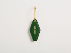 a green keychain with the word est 707 on it hanging from a hook