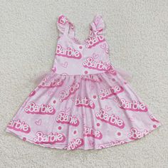 a pink dress with the word barbie written on it and hearts all over it, sitting on a white carpet