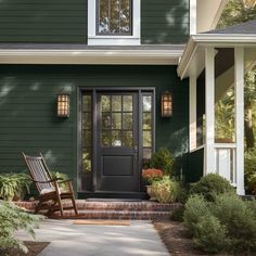 a green house with a rocking chair on the front porch and steps leading up to it