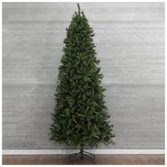 a small christmas tree on a stand in front of a white wall and wooden floor