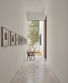 an empty hallway with pictures on the wall and a bench in front of one door