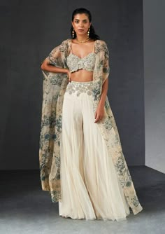 Editor's Note Presenting an exquisite ensemble: a champagne-blue cape that gracefully complements an ambi jaal embroidered bustier and an embroidered waist net sharara. This ensemble effortless... Sharara And Cape, Festive Organza Lehenga With Cape Sleeves, Embroidered Sharara With Cape Sleeves For Festive Occasions, Festive Embroidered Palazzo Set With Cape Sleeves, Anarkali Set With Sheer Dupatta And Cape Sleeves, Bollywood Embroidered Palazzo Set With Cape Sleeves, Designer Lehenga With Resham Embroidery And Cape Sleeves, Anarkali Set With Intricate Embroidery For Reception, Fitted Sharara With Sheer Dupatta And Cape Sleeves