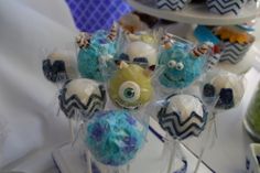 cake pops decorated with blue and white frosting are displayed in front of other desserts