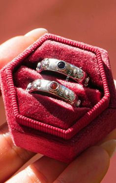 two silver rings in a red velvet ring box, with black stones on each one