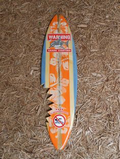 an orange and blue surfboard laying on some straw