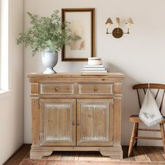 a room with a chair, table and pictures on the wall next to a potted plant