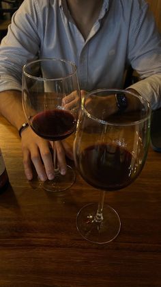 a man sitting at a table with two wine glasses