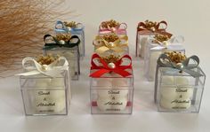 four small clear boxes with different designs and ribbons on them, each containing an ornament