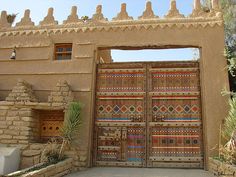 an adobe style building with two large wooden doors and decorative designs on the front door