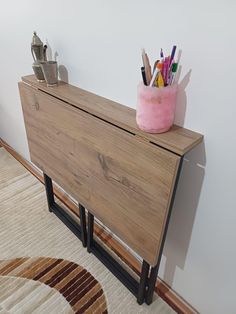 a wooden cabinet sitting on top of a rug next to a wall with pens and pencils in it