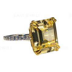 a fancy yellow diamond ring with diamonds on the sides and an oval cut stone in the center