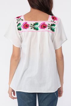 "Vintage Mexican blouse with floral embroidery on white cotton. Tunic cut. Every garment we sell is authentic vintage and one-of-a-kind! You will receive the exact item photographed. Condition: Very good vintage. Has a couple faint spots that should come out with cleaning. Best fits women's: Extra small Material: Feels like Cotton MEASUREMENTS Taken from seam to seam while the garment is lying flat. Double the armpit, waist, and hips For reference, model is 5'9\" and measures 33-25-36. Length fr White Bohemian Peasant Top With Chikankari Embroidery, White Chikankari Embroidered Top For Festival, Folk Style Peasant Top With Floral Embroidery For Beach, White Peasant Embroidered Top For Summer, White Floral Print Peasant Top, White Bohemian Embroidered Cotton Top, White Bohemian Embroidered Top For Festival, Cotton Folk Peasant Top For Beach, Folk Style Cotton Peasant Top For Beach