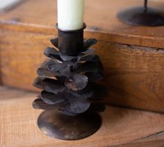 a pine cone candle holder sitting on top of a wooden table