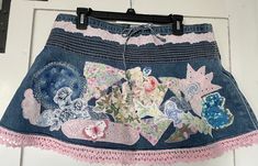 This whimsical denim skirt is appliquéd with assorted vintage fabrics, doilies, and lace. It is trimmed at the top with a beautiful pink floral trim and at the bottom with a lovely pink crocheted lace. Size 10. Jeans Rock, Denim Mini Skirt, Vintage Fabrics, Crochet Lace, Pink Floral, Denim Skirt, Womens Skirt, Pattern Design, Mini Skirts