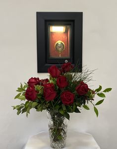 a vase filled with red roses sitting on top of a table