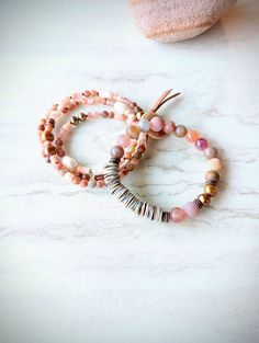 First, at almost 22" in length, this beaded strand can be worn as a necklace and a triple wrap bracelet if you like. Muted pinks, grays, beige, gold, desert rose, touches of orange, rust, maroon, beige, and more. A great mix of washed out color like a desert sunset. 6mm to 11mm Pearl, matte 4mm Agate, matte Sunstone, matte 4mm Jasper stones, sunstone and Quartz heishi beads, accents of matte gold seed beads, and metals. Distressed natural suede loops and coconut button closure make extendable. O Adjustable Rondelle Beaded Necklaces As Gifts, Agate Gemstone Beads Jewelry For Layering, Hand Wrapped Agate Round Bead Jewelry, Adjustable Necklace For Layering, Adjustable Agate Beaded Necklace With Natural Stones, Wrap Bracelet With Round Natural Stones, Adjustable Hand Wrapped Beaded Bracelets, Adjustable Hand Wrapped Beaded Bracelets For Layering, Adjustable Spiritual Jewelry With Faceted Beads