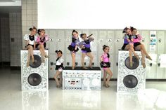 the girls are posing on speakers in front of lockers