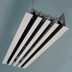 an overhead view of four black and white umbrellas against a blue sky with clouds in the background