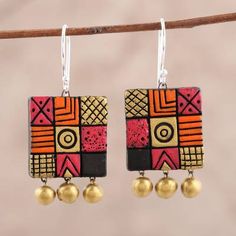 two pairs of colorful earrings hanging from a tree branch with gold balls and beads on it