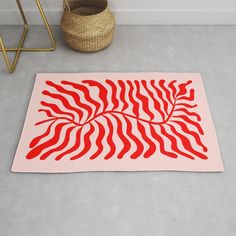 a red and white rug on the floor next to a basket with a plant in it