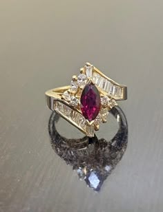 DeKara Designs Classic A ring my father Setrag Karadolian designed and made himself over 30 years that is back in fashion today! Beautiful Art Deco Ruby and Diamond Ring Handmade By A True Artist. Metal- 14K Yellow Gold, .583 Stones- 1 Natural Marquise Shaped Ruby Red in Color 0.85 Carats, 14 Baguette Diamonds, 4 Marquise Diamonds, 4 Round Diamonds, G-H Color VS1-VS2 Clarity 1.15 Carats. Handmade 14K Yellow Gold Marquise Ruby Baguette, Marquise, and Round Diamond Engagement Ring. This ring featu Luxury Marquise Cut Ruby Ring Fine Jewelry, Diamond Ring With Ruby Side Stones, Ruby Engagement Ring Art Deco, Ruby Ring With Diamonds, Ruby Marquise Engagement Ring, Art Deco Gemstone Ring, Wedding Ring Art Deco, Ruby Art Deco Ring, Vintage Marquise Cut Multi-stone Jewelry