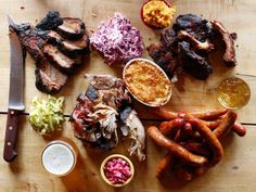 a wooden table topped with meat and veggies next to a knife on top of it