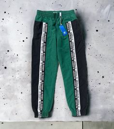 New with tags Adidas RYV Blacked TP green track pants, size Large. Pants in photos are the pants that will ship. See photos for measurements to ensure proper fit. Ships fast from a smoke-free home by USPS Ground Advantage. WOVEN PANTS INSPIRED BY '90S STREETWEAR. Modern comfort with a retro twist. Inspired by '90s sportswear, these track pants have a bold logo look with branded tape on the front. They're made of soft, lightweight plain weave and cut for a relaxed easy-to-wear shape. Relaxed fit Adidas Jogging Bottoms With Side Stripes, Adidas Bottoms With Side Stripes For Jogging, Green Streetwear Pants With Side Stripes, Green Side Stripe Pants For Streetwear, Green Pants With Side Stripes For Streetwear, Adidas Green Bottoms For Streetwear, Green Athleisure Cargo Pants For Sports, Green Sweatpants With Side Stripes For Streetwear, Green Cotton Cargo Pants For Sports