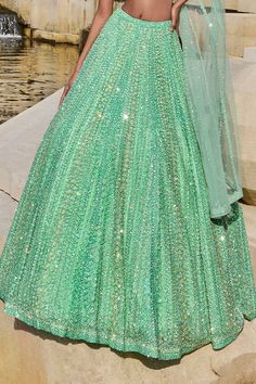 Sea green lehenga in a net base with attached can-can and all-over tonal stripe pattern sequin embroidery. Comes with one shoulder padded blouse with attached drape.
Components: 2
Pattern: Embroidery
Type Of Work: Sequin
Neckline: One Shoulder
Sleeve Type: Sleeveless
Fabric: Net
Color: Green
Other Details: 
Lehenga Length: 45 inches
Blouse with attached drape at the back
Sequin embroidery all-over
Occasion: Bride - Aza Fashions Sea Green Lehenga, Seema Gujral, Net Embroidery, Green Lehenga, Padded Blouse, Sequin Embroidery, Pattern Embroidery, Sequins Embroidery, Fashion App