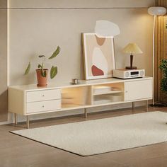 a living room with white furniture and plants on the sideboard in front of it