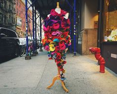 a mannequin made out of colorful pieces of clothing on a sidewalk next to a fire hydrant