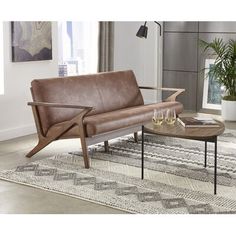 a brown leather couch sitting on top of a rug next to a wooden coffee table