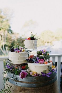 three tiered wedding cake sitting on top of a barrel