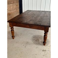 an old wooden table sitting in front of a white corrugated wall with wood trimming