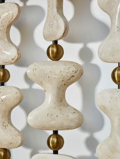 an assortment of white and gold vases hanging from a metal rod on a wall