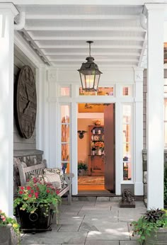 a porch with potted plants on the side and a clock hanging from the ceiling