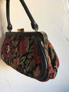 "1950s classic carpet bag structured bag originally designed for the classic woman with a boho soul. Vintage fall leaves and floral with black needlepoint carpet bag with leather strap and edging. Brass metal clasp and hardware has an authentic patina. Black fabric lining with a single zippered security pocket. Unmarked Size: 7\" tall x 12.5\" wide x 4.5\" deep at base. Handle is a total of 12\" for about a 5\" -6\" drop. Condition: Vintage excellent with obvious patina. Inside there is a very s Vintage Tote Shoulder Bag For Fall, Vintage Rectangular Bags For Fall, Vintage Brown Satchel For Fall, Vintage Tapestry Bag For Everyday, Vintage Shoulder Bag For Daily Use In Fall, Vintage Top Handle Satchel With Brass Hardware, Vintage Tapestry Shoulder Bag For Travel, Vintage Formal Bags For Fall, Vintage Formal Fall Bags