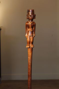 a wooden statue standing on top of a hard wood floor