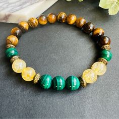 Unisex Stretch Beaded Bracelet Features 8mm Round Beads Made Of Natural Green Malachite, Yellow Citrine, And Brown Tigers Eye. The Combination Of These Three Stones Creates A Unique And Eye-Catching Design. The Stretchy Band Ensures A Comfortable Fit For Most Wrist Sizes. This Bracelet Is Perfect For Adding A Pop Of Color To Any Outfit And Makes A Great Gift For Any Jewelry Lover. Yellow Round Bead Bracelets For Everyday, Yellow Round Beads Bracelet For Everyday, Yellow Beaded Bracelets For Everyday, Yellow Beaded Bracelets With Round Beads For Everyday, Bohemian Yellow Beaded Bracelets With Natural Stones, Yellow Hand-strung Jewelry For Meditation, Adjustable Yellow Beaded Bracelets With Natural Stones, Yellow Stretch Bracelet With Round Beads As Gift, Handmade Yellow Spiritual Bracelets