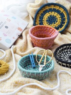 three baskets are sitting on a blanket with yarn and scissors