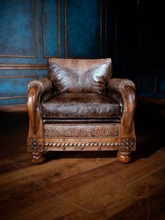 a brown leather chair sitting on top of a wooden floor next to a blue wall