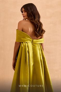 a woman in a yellow dress with her back turned to the camera and looking off into the distance