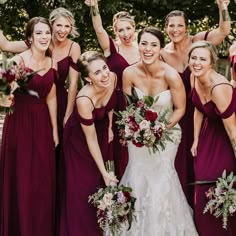 a group of women standing next to each other holding bouquets and posing for the camera