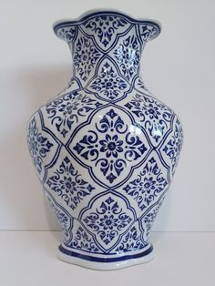 a large blue and white vase sitting on top of a table next to a wall